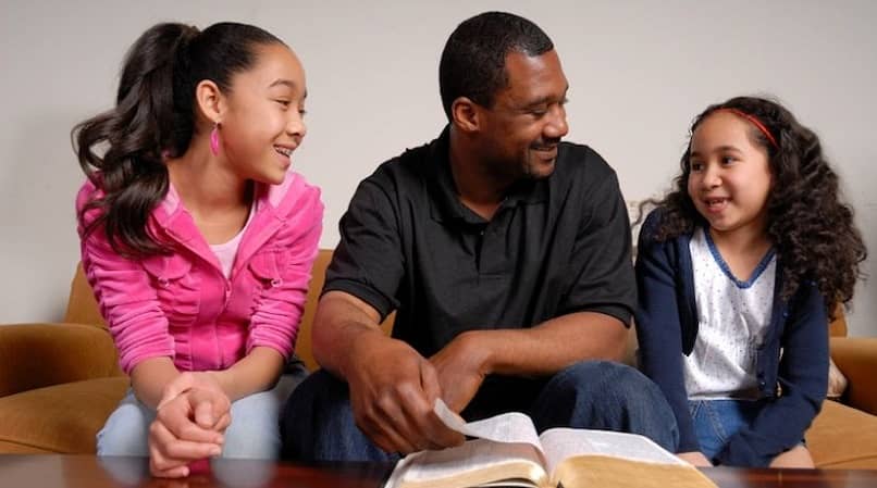 padre enseñandole la biblia a su hijas